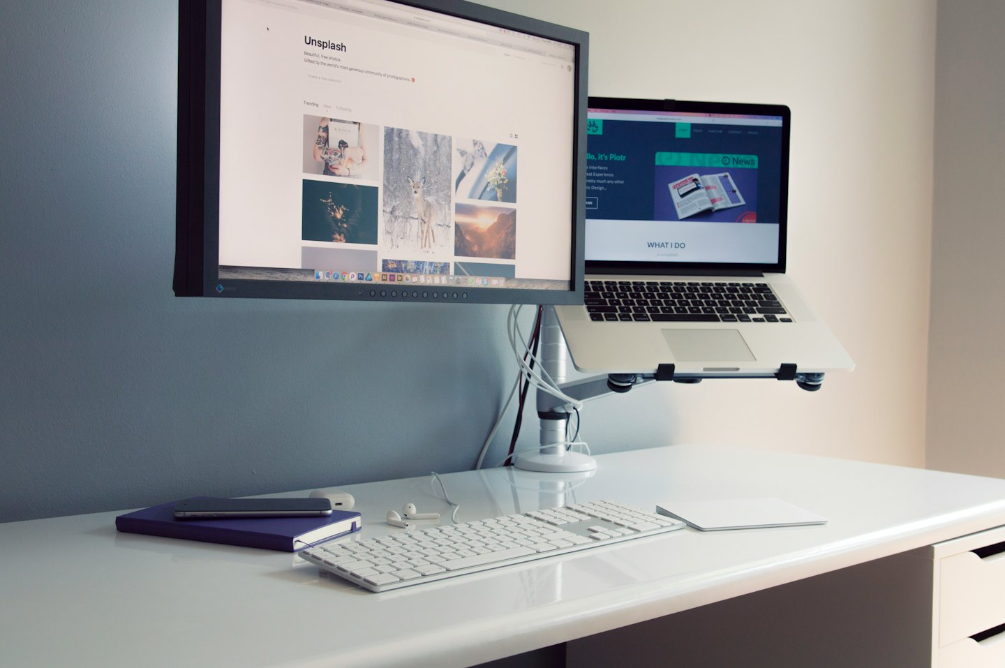 Uporządkowane biurko z dwoma monitorami i podstawką na laptopa.