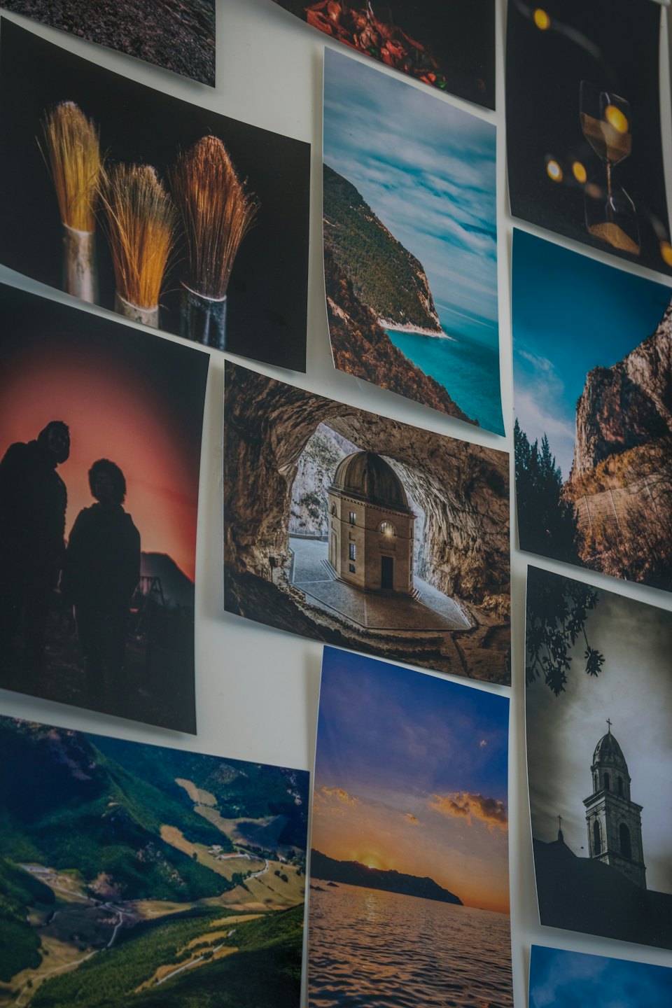 Wydrukowane fotografie ułożone w siatkę na białej ścianie.